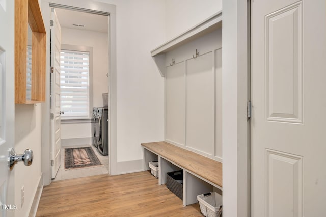 mudroom with independent washer and dryer and light hardwood / wood-style floors