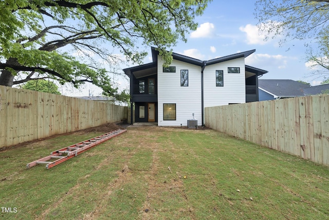 back of property with central AC and a lawn