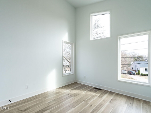 spare room with light wood-type flooring and a wealth of natural light