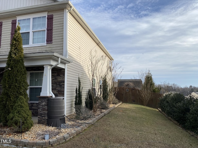 view of property exterior featuring board and batten siding, stone siding, and fence