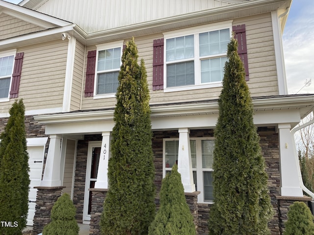 view of side of home featuring stone siding and covered porch