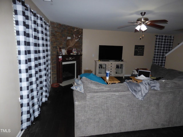 living area with a ceiling fan, dark wood-style flooring, and a fireplace