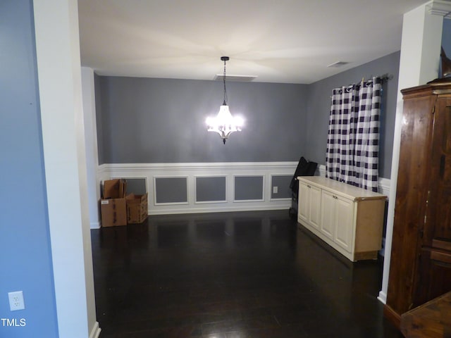 dining space featuring dark wood-type flooring, wainscoting, visible vents, and a chandelier