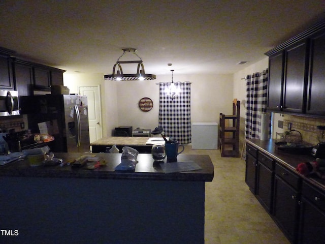 kitchen featuring stainless steel appliances, dark countertops, and decorative light fixtures