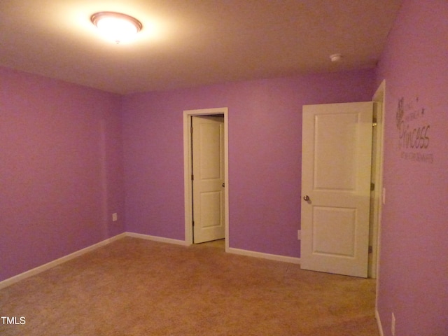 unfurnished room featuring light carpet and baseboards