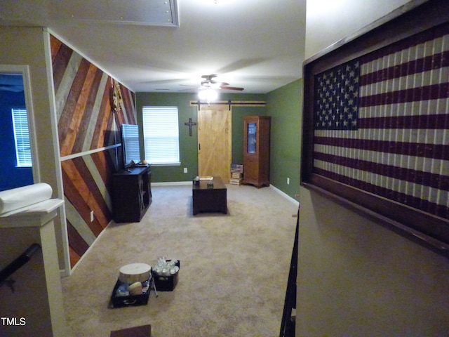 carpeted living area featuring attic access, ceiling fan, baseboards, and a barn door