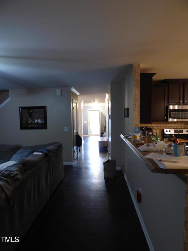 kitchen featuring dark brown cabinetry, tasteful backsplash, appliances with stainless steel finishes, and baseboards