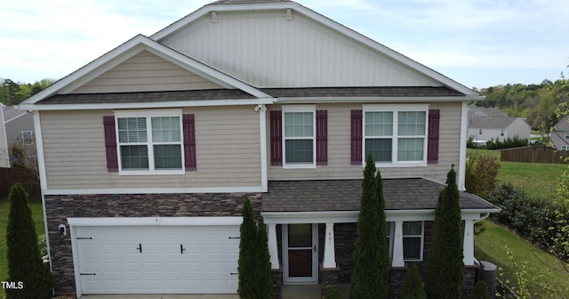 craftsman inspired home featuring an attached garage, concrete driveway, a shingled roof, and stone siding