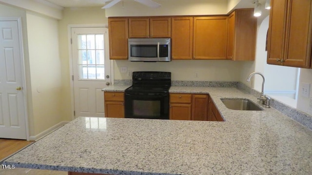 kitchen featuring kitchen peninsula, light stone countertops, black range with electric stovetop, ceiling fan, and sink