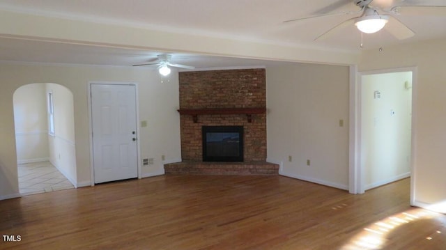 unfurnished living room featuring a fireplace, ceiling fan, and light hardwood / wood-style floors