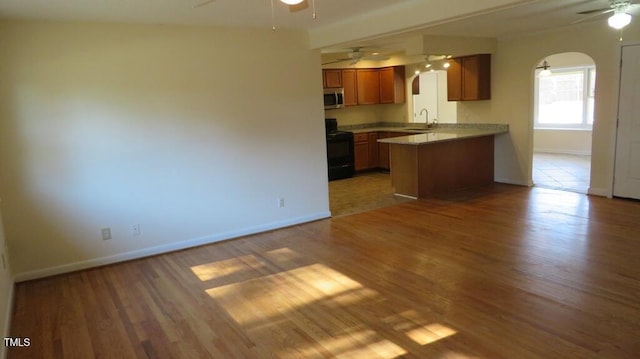 kitchen featuring electric range, wood-type flooring, kitchen peninsula, ceiling fan, and sink