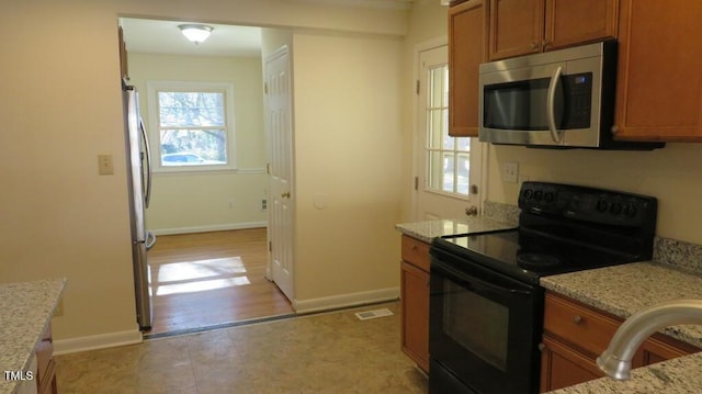 kitchen featuring light stone counters, stainless steel appliances, and a healthy amount of sunlight