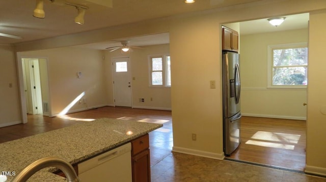 kitchen featuring a healthy amount of sunlight, stainless steel fridge with ice dispenser, light stone counters, and ceiling fan