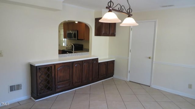 kitchen featuring light tile patterned floors, pendant lighting, sink, and dark brown cabinetry