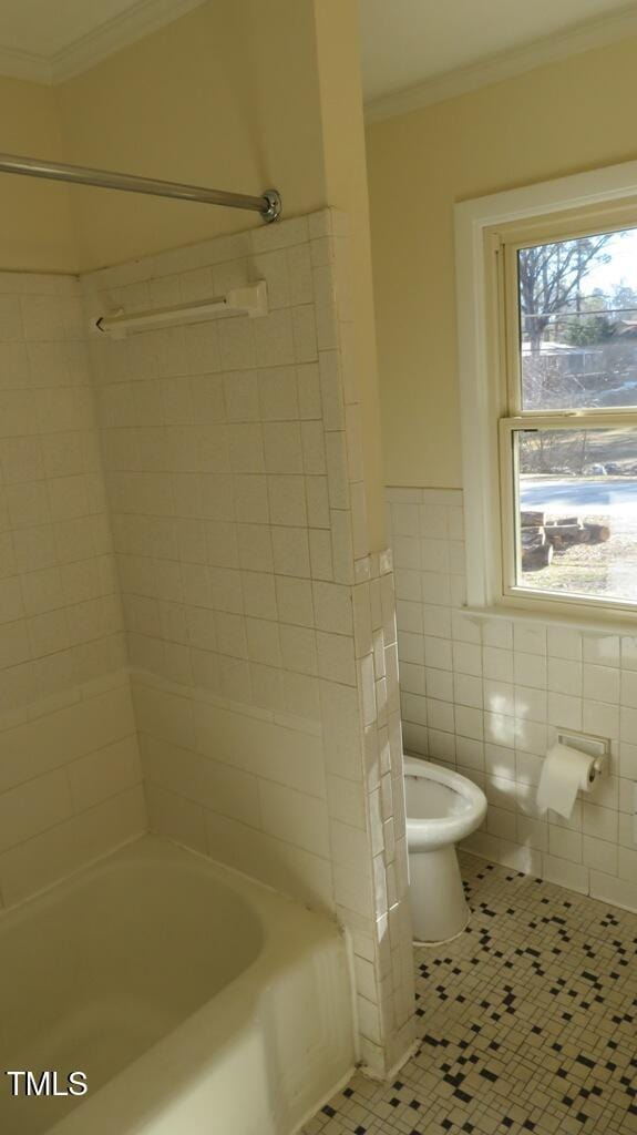 bathroom featuring tile patterned flooring, toilet, tile walls, ornamental molding, and tiled shower / bath