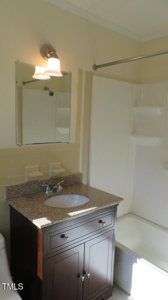 bathroom with tile walls, backsplash,  shower combination, vanity, and crown molding