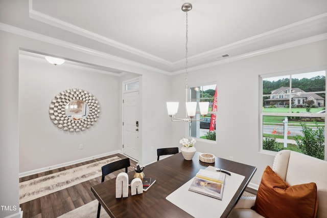 dining space with a raised ceiling, ornamental molding, hardwood / wood-style flooring, and a notable chandelier