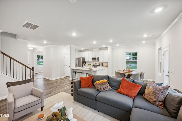 living room with sink, light wood-type flooring, and crown molding