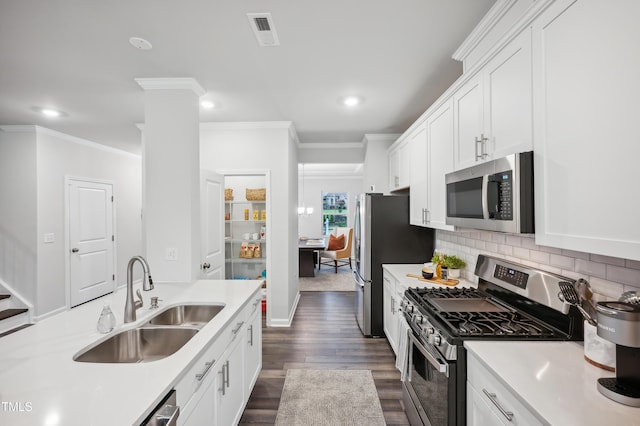 kitchen featuring sink, white cabinetry, backsplash, crown molding, and appliances with stainless steel finishes