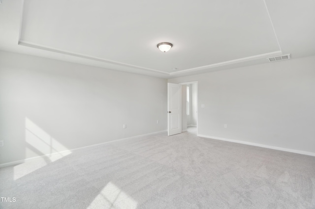 carpeted spare room featuring a raised ceiling