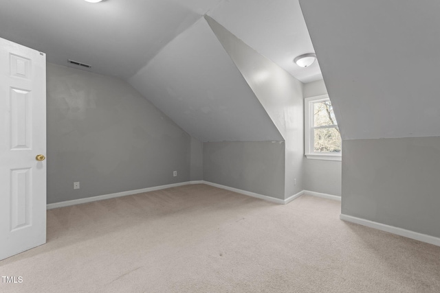 bonus room with light colored carpet and vaulted ceiling