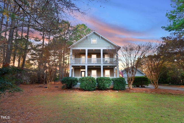 greek revival inspired property featuring covered porch, a balcony, and a yard