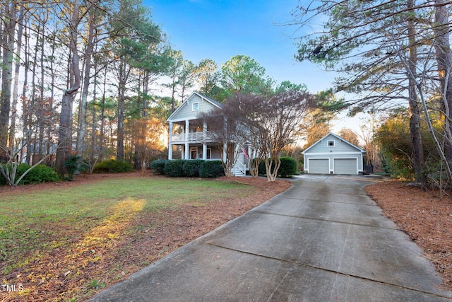 view of front facade with a porch, a balcony, a front lawn, an outbuilding, and a garage