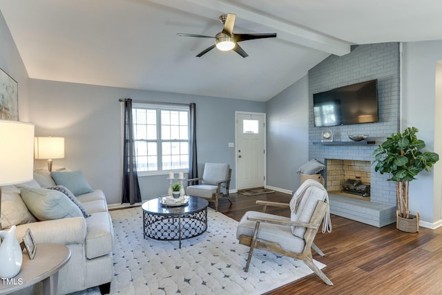 living room featuring a brick fireplace, dark wood-type flooring, vaulted ceiling with beams, and ceiling fan