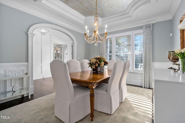 dining room featuring ornamental molding, wood-type flooring, a tray ceiling, and a notable chandelier