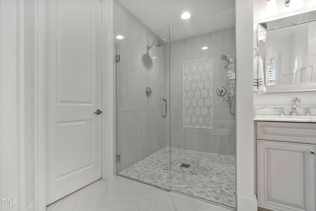 bathroom featuring a shower with shower door and vanity