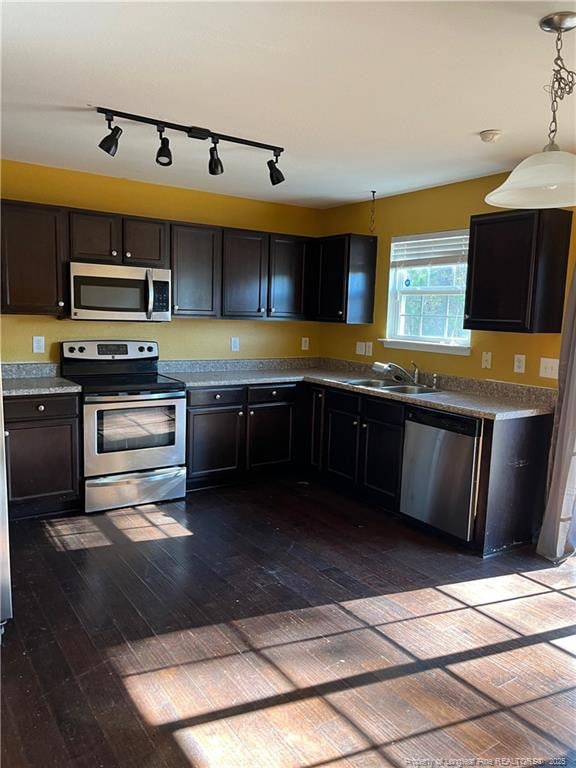 kitchen with stainless steel appliances, hanging light fixtures, dark hardwood / wood-style floors, sink, and dark brown cabinets