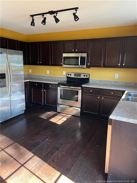 kitchen with appliances with stainless steel finishes, dark hardwood / wood-style flooring, and dark brown cabinets