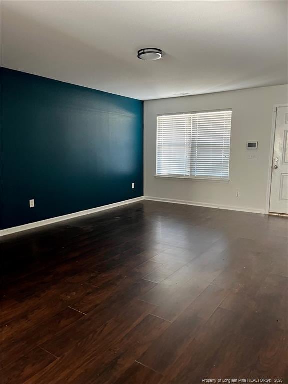 unfurnished room with baseboards and wood finished floors