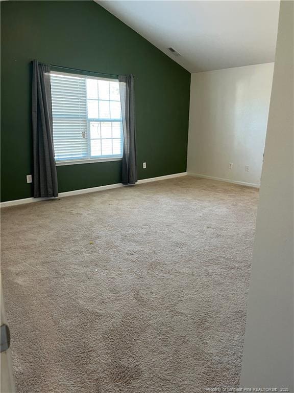 empty room with carpet, baseboards, vaulted ceiling, and visible vents