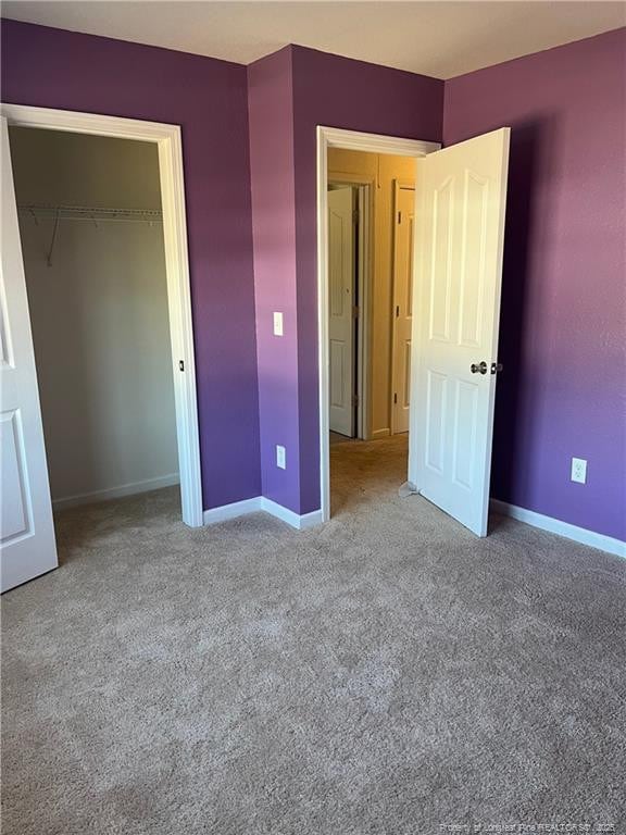 unfurnished bedroom with carpet floors, baseboards, and a closet