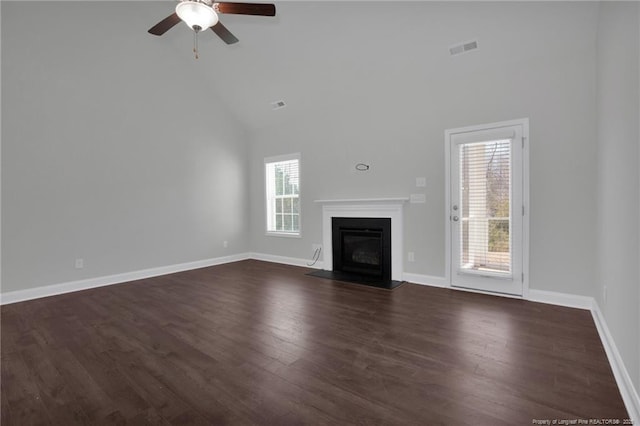 unfurnished living room with high vaulted ceiling, dark hardwood / wood-style flooring, ceiling fan, and plenty of natural light