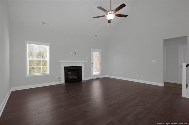 unfurnished living room featuring a high ceiling, dark wood-type flooring, and ceiling fan