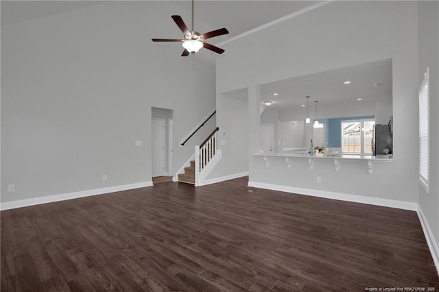 unfurnished living room featuring high vaulted ceiling, dark hardwood / wood-style flooring, and ceiling fan