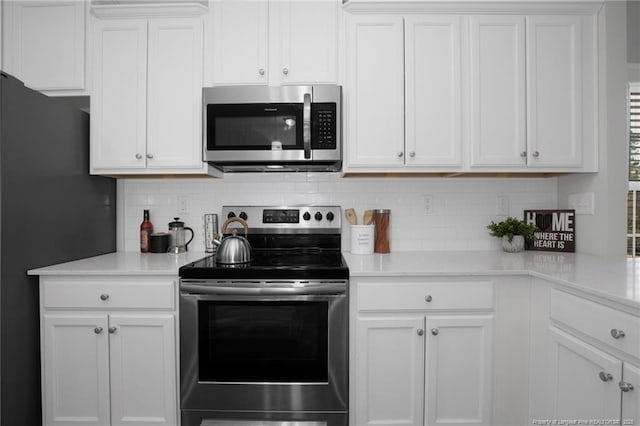 kitchen with white cabinets, appliances with stainless steel finishes, and tasteful backsplash