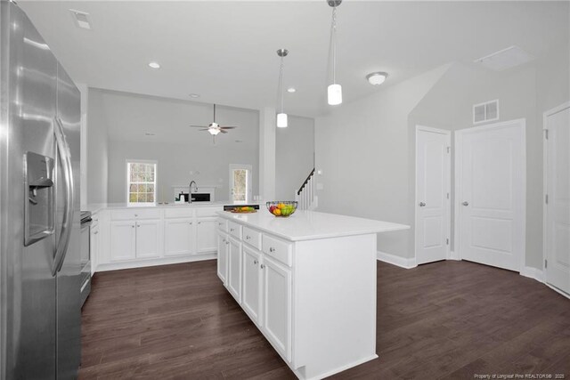 kitchen with appliances with stainless steel finishes, a center island, kitchen peninsula, white cabinetry, and decorative light fixtures