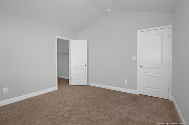 unfurnished bedroom featuring vaulted ceiling, a closet, and carpet flooring