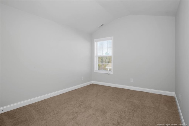 empty room featuring vaulted ceiling and carpet floors