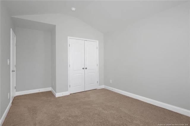 unfurnished bedroom with lofted ceiling, carpet flooring, and a closet