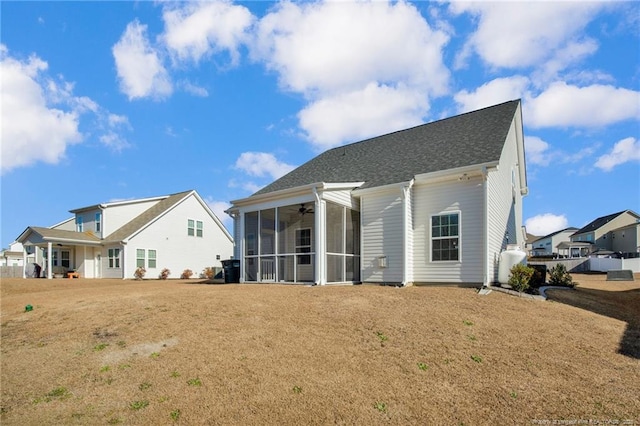 rear view of house featuring a lawn and a sunroom