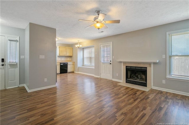 unfurnished living room with ceiling fan with notable chandelier, a textured ceiling, and dark hardwood / wood-style flooring