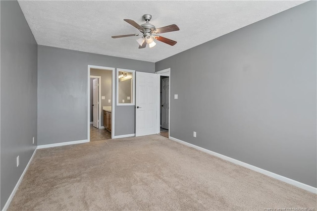 unfurnished bedroom featuring ensuite bathroom, light colored carpet, ceiling fan, and a textured ceiling