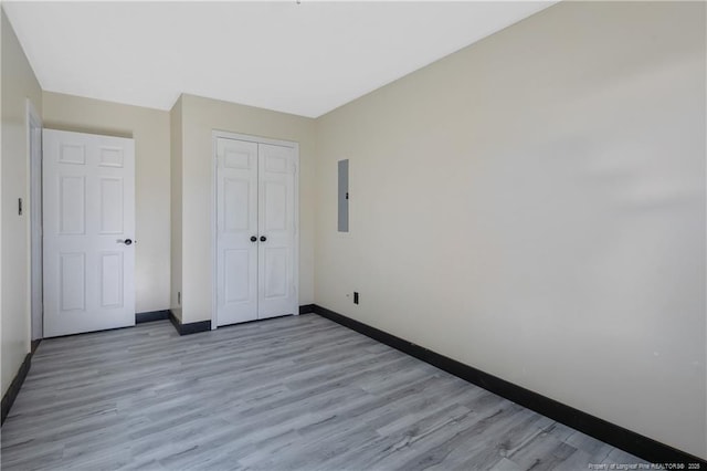 unfurnished bedroom featuring electric panel, a closet, and light hardwood / wood-style flooring