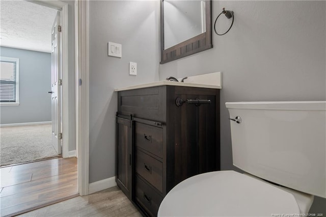 bathroom featuring toilet, wood-type flooring, vanity, and a textured ceiling