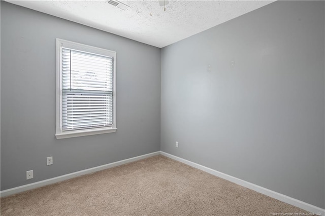 spare room featuring a textured ceiling and light carpet