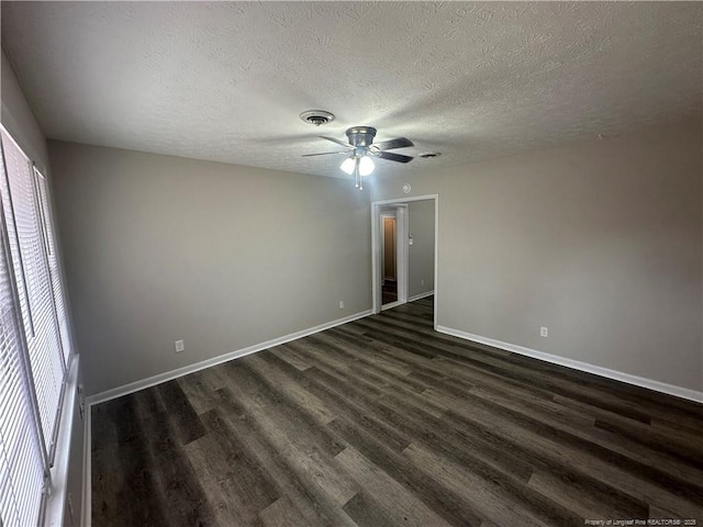 unfurnished bedroom featuring ceiling fan, dark hardwood / wood-style flooring, multiple windows, and a textured ceiling